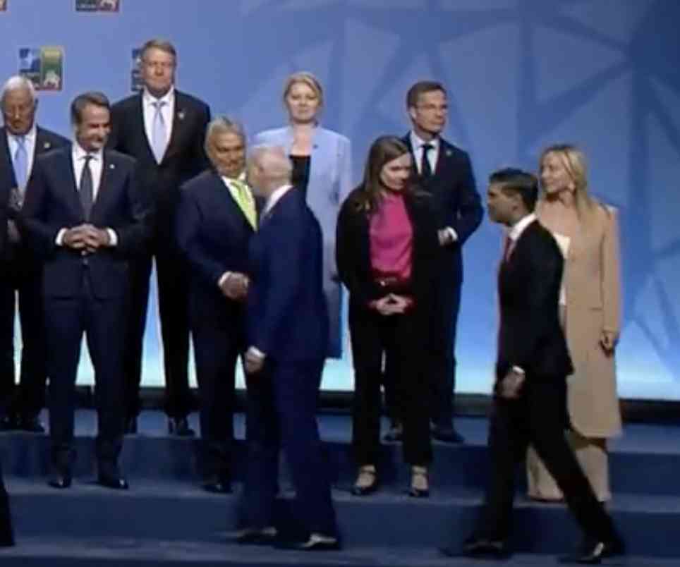 Itt látható a valódi felvétel, ahol az amerikai elnök kezet fog Orbánnal, miközben bevonul mindenki a terembe.